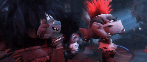 a group of trolls are standing next to each other in a dark room and singing .