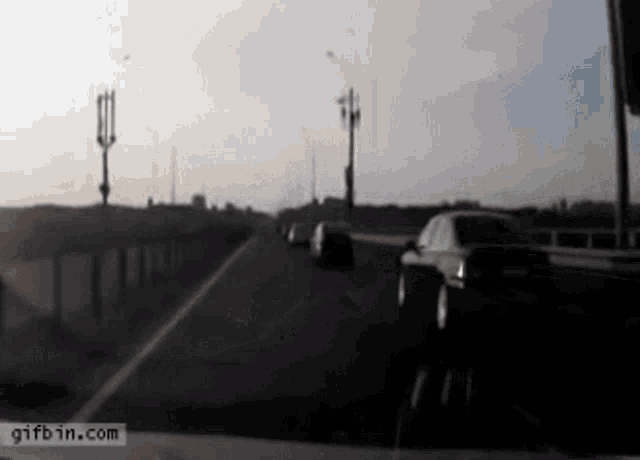 a car is driving down a highway with a gifbin.com watermark on the bottom