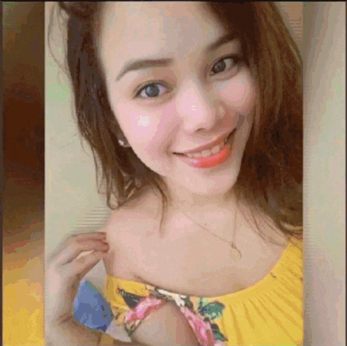 a woman in a yellow off the shoulder top smiles