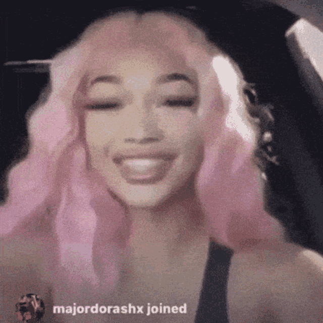 a woman with pink hair is smiling in a car with majordorashx joined in the bottom right corner