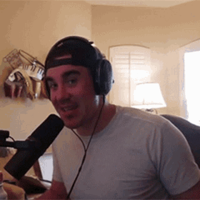 a man wearing headphones and a baseball cap is talking into a microphone