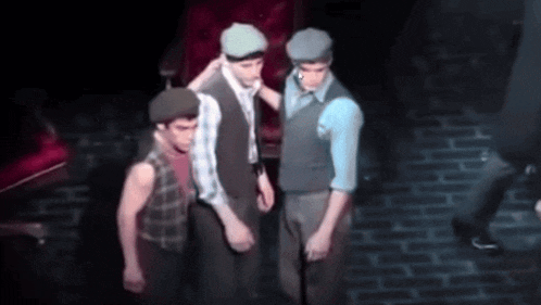 a group of men standing on a stage with one wearing a beret