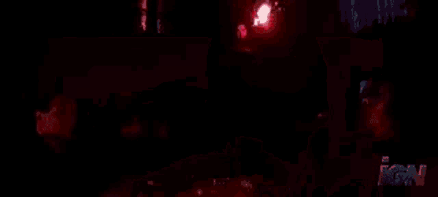a man is standing in a dark room with a red light shining on him .