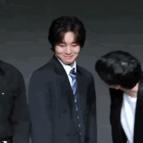 two men in suits and ties are standing next to each other smiling .