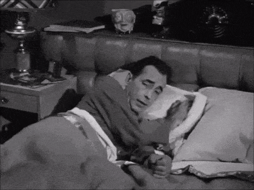 a black and white photo of a man sleeping in bed