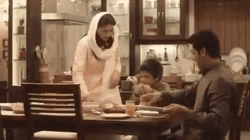 a man and a woman are sitting at a table with a child eating food .