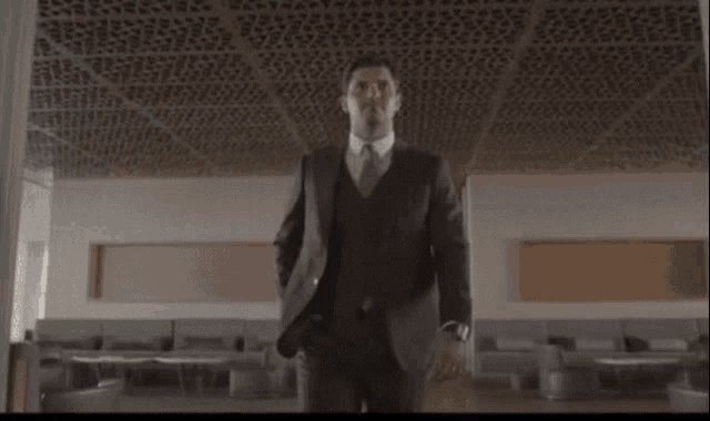 a man in a suit and tie is standing in a hallway .