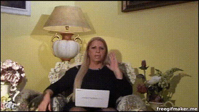 a woman is sitting in front of a lamp and holding a piece of paper that says " freegifmaker.me "