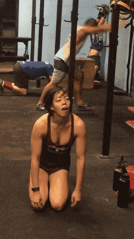 a woman kneeling down in a gym with a tank top that says eagles on it