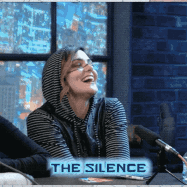 a woman is laughing in front of a microphone with the words the silence below her