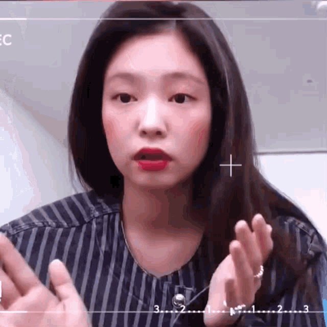 a woman wearing a striped shirt and red lipstick is making a funny face