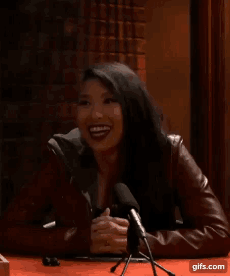 a woman sitting in front of a microphone smiling