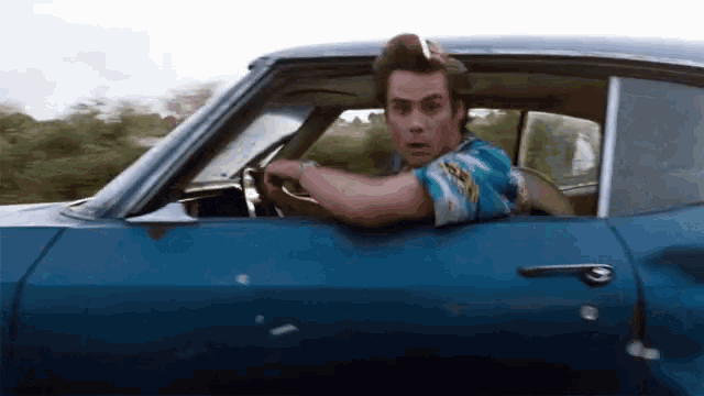 a man in a blue shirt is driving a blue car
