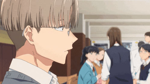 a boy with glasses is standing in a hallway with other people