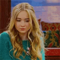 a woman with long blonde hair is wearing a green sweater and a necklace .