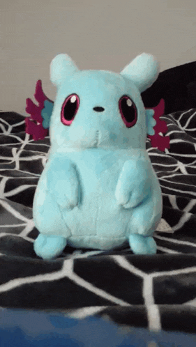 a stuffed animal is sitting on a bed with a patterned blanket