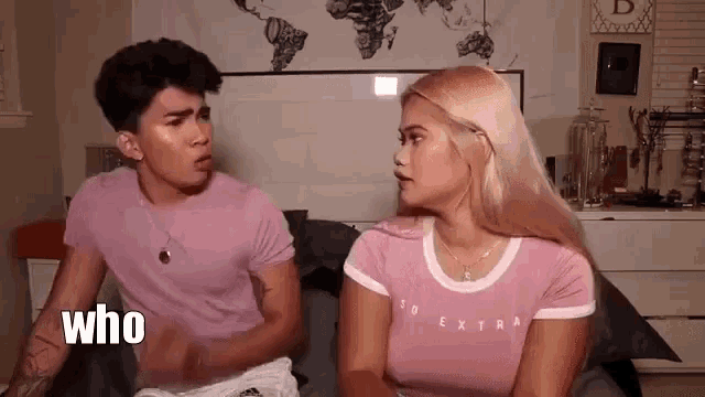 a man and a woman are sitting next to each other on a bed . the woman is wearing a pink shirt .