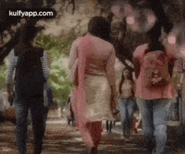 a group of people are walking down a sidewalk in a city .