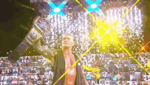 a wrestler is holding a world heavyweight championship belt in front of a crowd .