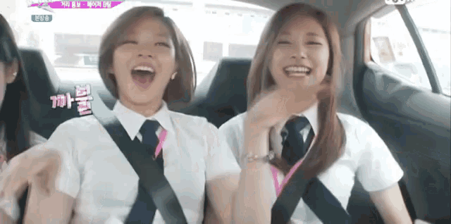 two girls are sitting in the back seat of a car laughing