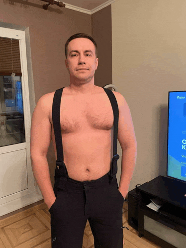 a shirtless man wearing suspenders stands in front of a television screen that says ox