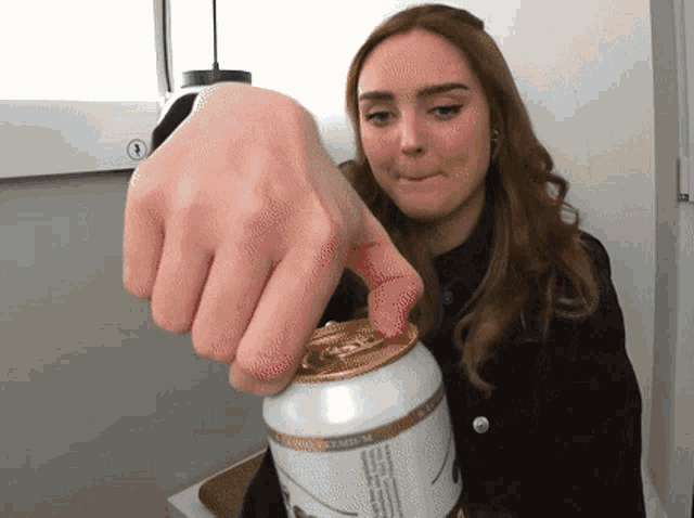 a woman is opening a can of beer that says ' premium ' on it