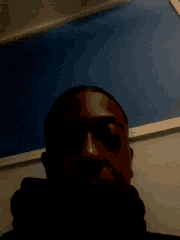 a close up of a person 's face with a blue wall in the background