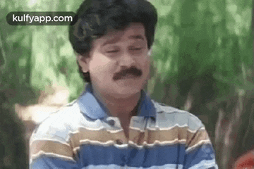 a man with a mustache is wearing a striped shirt and making a face .