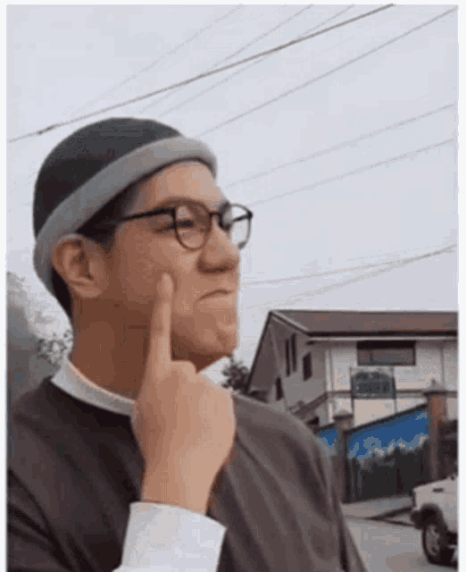a man wearing glasses and a beanie is making a funny face