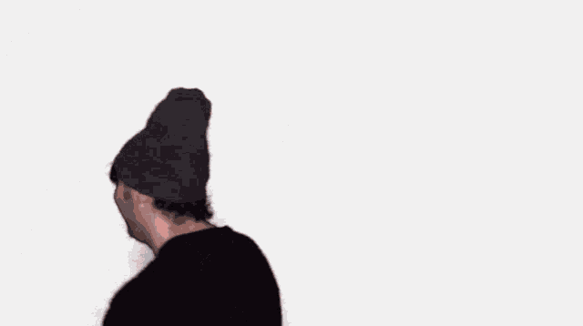 a man wearing a hat and a plaid sweater smiles
