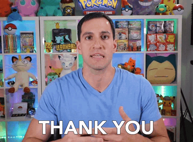 a man in a blue shirt says thank you in front of a pokemon display