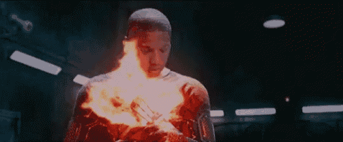 a man with a fireball coming out of his chest is standing in a dark room .