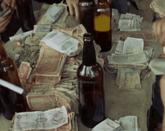 a bottle of beer sits on a table next to a stack of money