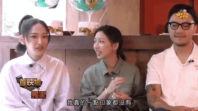 a man and two women are sitting next to each other with chinese writing on the wall behind them