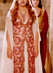 a woman in a white dress is standing next to another woman in a red and gold dress
