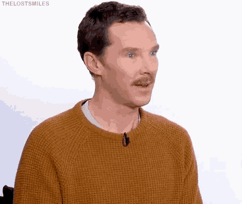 a man with a mustache is wearing a sweater and making a funny face .