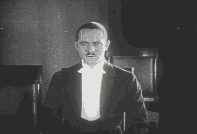 a man in a tuxedo and bow tie is looking at the camera