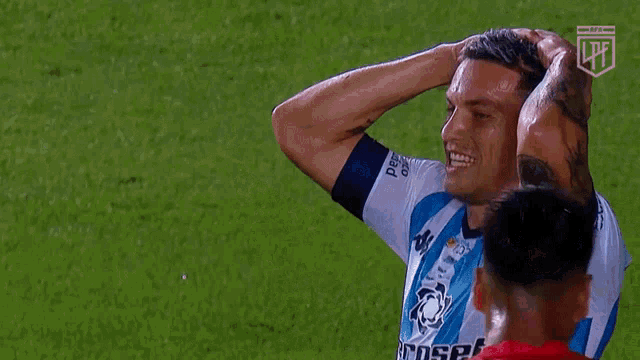 a man in a banco ciudad jersey holds his head