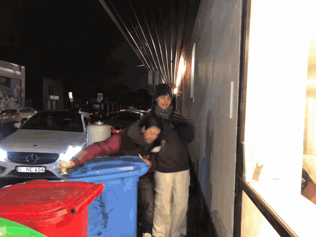 two people standing next to a trash can with a license plate that says ln - jc - 453