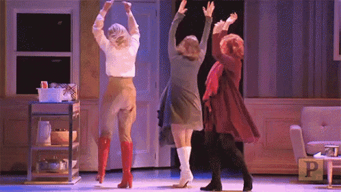 three women are dancing on a stage in front of a sign that says p on it