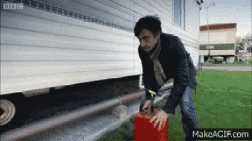 a man is pumping gas into a red container on make a gif