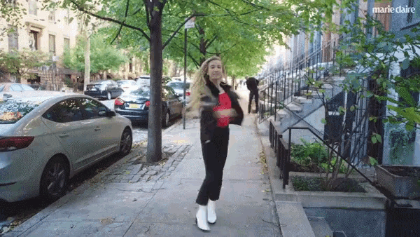 a woman dancing on a sidewalk in front of a marie claire logo