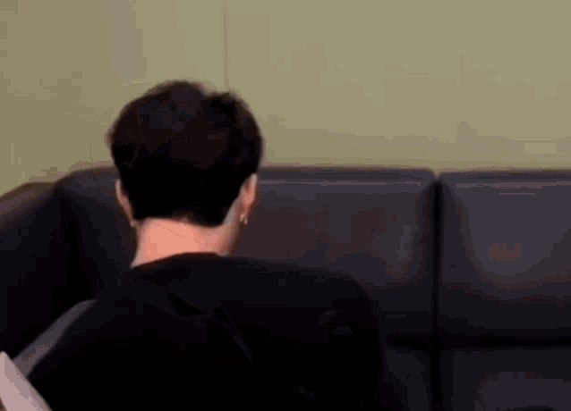 a man is sitting on a couch in a living room .