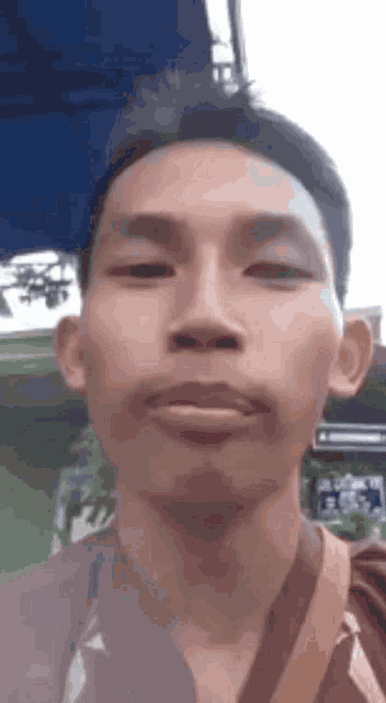 a man is making a funny face while taking a selfie with his phone .
