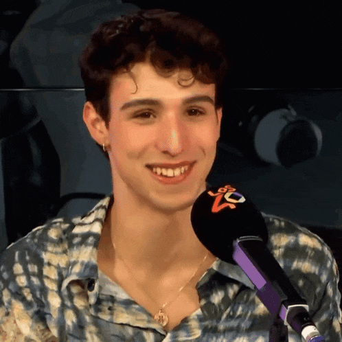 a young man is smiling in front of a microphone that says ' nc ' on it