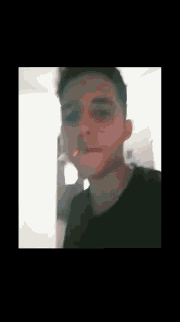 a man in a black shirt is smoking a cigarette in a room .