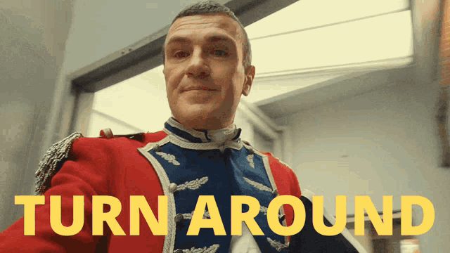 a man in a red and blue uniform stands in front of a sign that says " turn around "