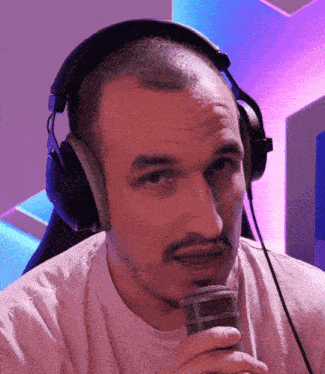 a man wearing headphones and holding a microphone looks at the camera
