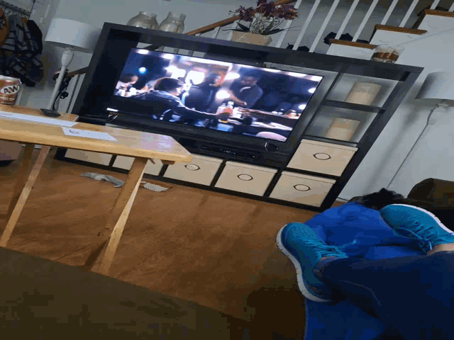 a person 's feet are on a blue blanket in front of a flat screen tv