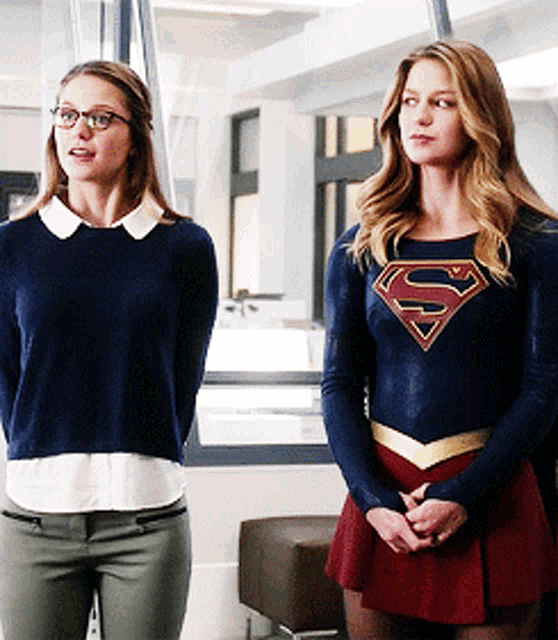 two women standing next to each other wearing superman costumes